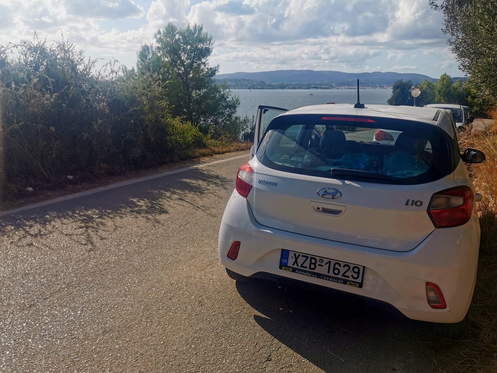 Un'auto bianca parcheggiata vicino al mare in Grecia.