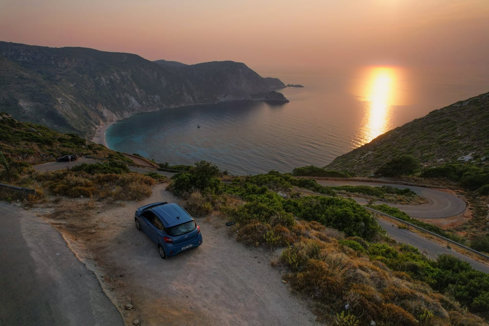 Un'auto parcheggiata in una baia durante il tramonto in Grecia.