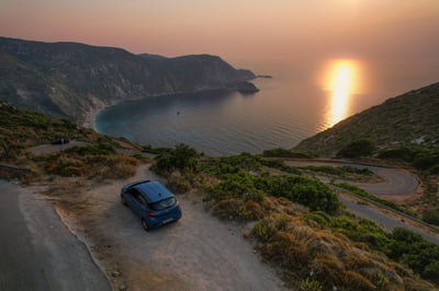 Un'auto parcheggiata in una baia durante il tramonto in Grecia.