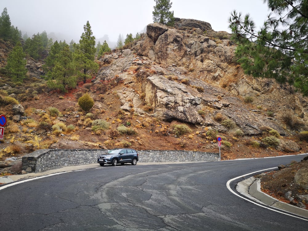 SUV grigio parcheggiato sul lato della strada vicino a montagne rocciose in Spagna